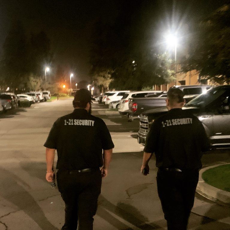 Uniformed security officers patrolling an apartment parking lot at night